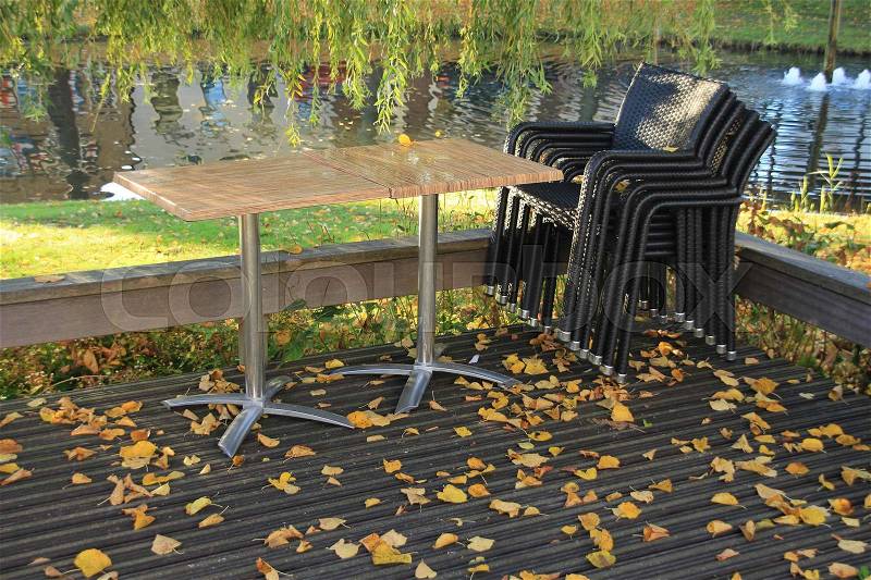 Platform with chairs and tables and many fallen leaves of the trees before the restaurant in the shopping centre in the village in autumn, stock photo