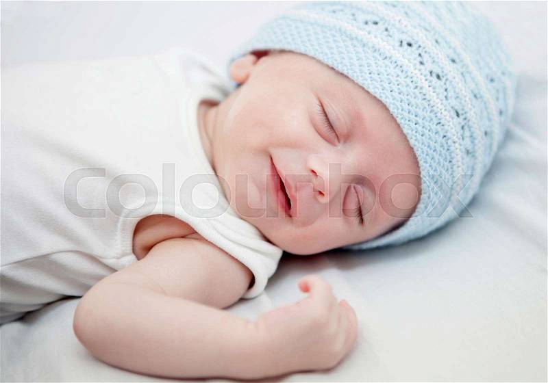 Beautiful baby with blue cap sleeping peacefully, stock photo
