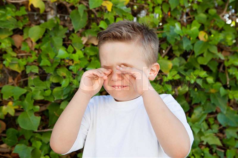 Blond little boy rubbing eyes for allergy, stock photo