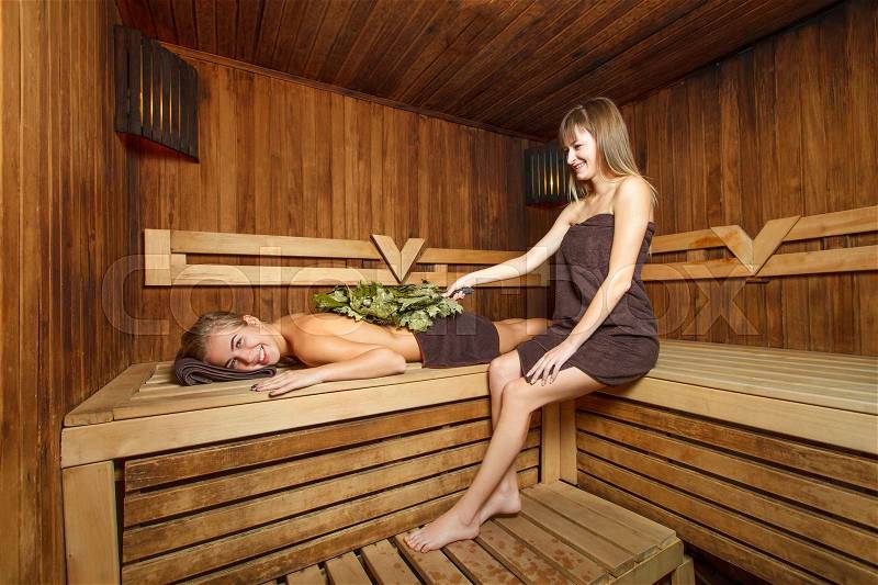Two young females take a steam bath in a sauna, stock photo