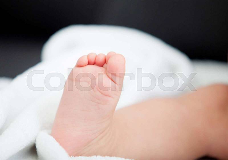 Little foot of a baby sitting on the sofa at home, stock photo