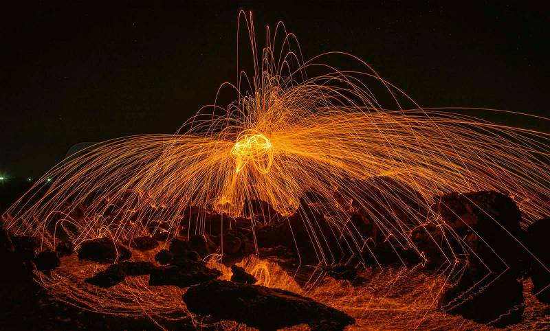 Burning steel wool on stone near the beach, stock photo