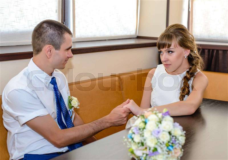 Young happy married couple sit at corner booth in restaurant by large windows, stock photo