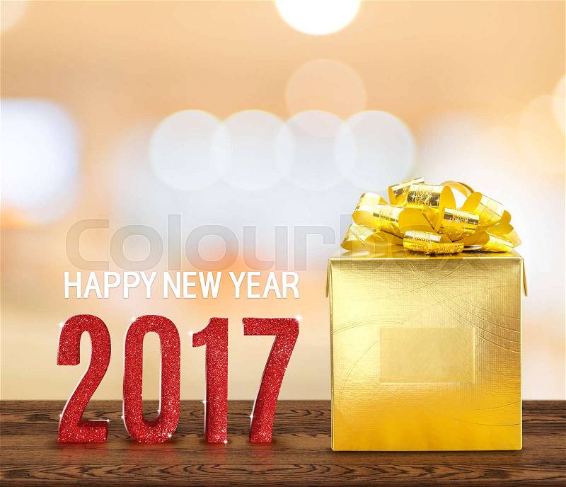 Happy new year 2017 wood number and golden present on brown wood table with gradient yellow bokeh light,Holiday concept, stock photo