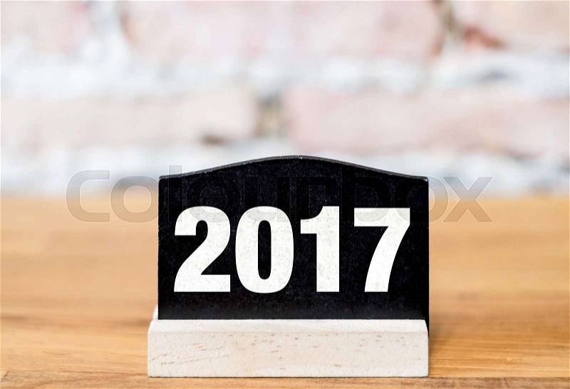 New year 2017 number on blackboard sign on wood table at brick wall, stock photo