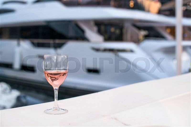 Glass of rose wine and a yacht on the background, stock photo