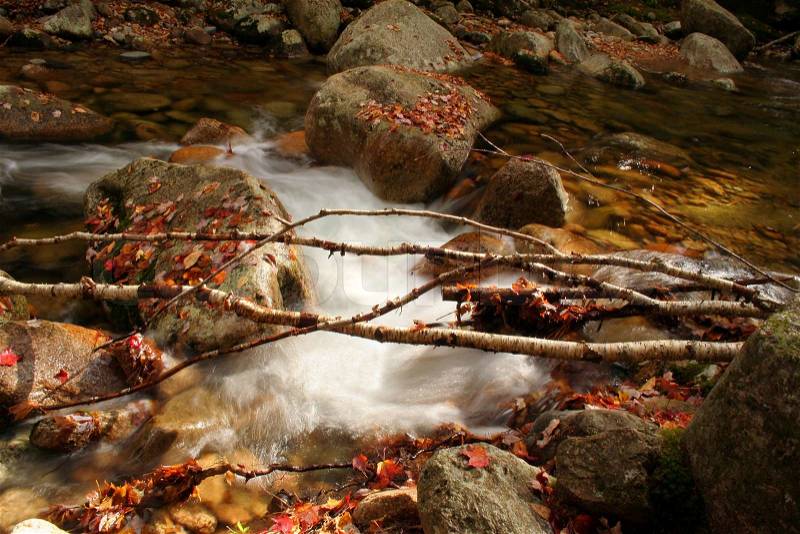 Soft swirling water over rocks in autumn, stock photo