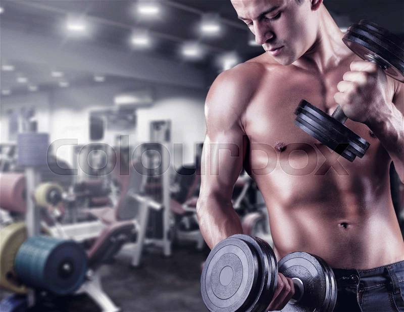 Closeup of a handsome muscular young man lifting weights in the gym, stock photo
