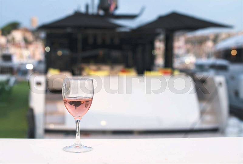 Glass of rose wine and a yacht on the background, stock photo