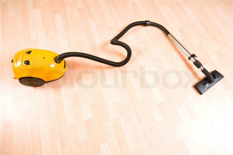 Vacuum cleaner on the polished wooden floor, stock photo