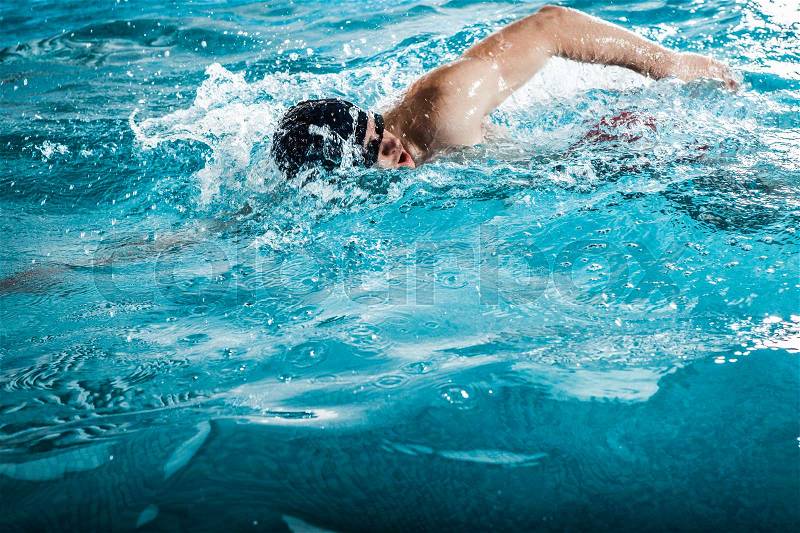 Young man swimming the front crawl in a pool, stock photo