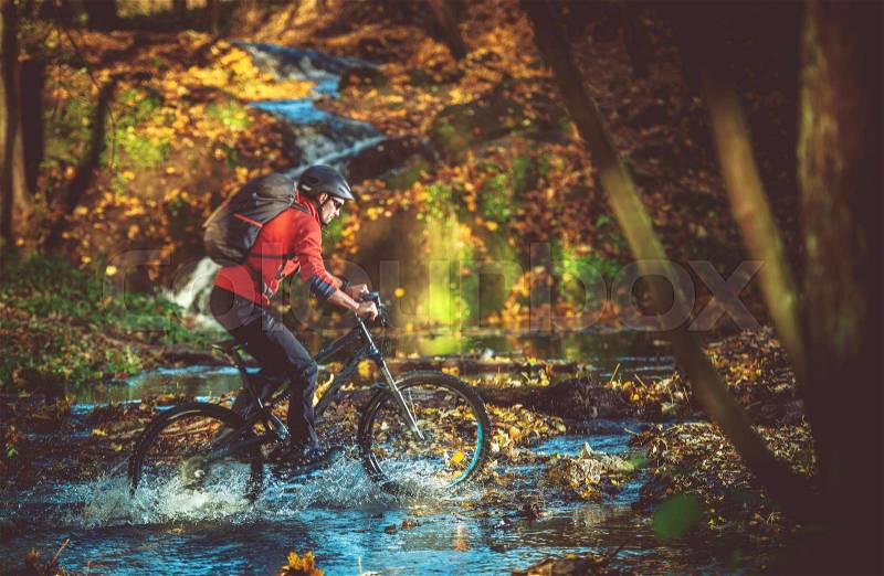 Bike RIde in the Scenic Fall Foliage Forest. Forest River Crossing. Caucasian Mountain Biker, stock photo