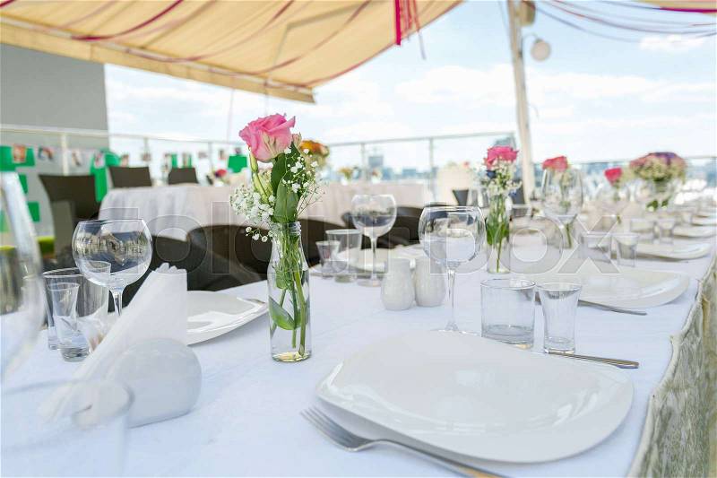 Closeup image of set table decorated for wedding banquet on outdoor summer terrace, stock photo