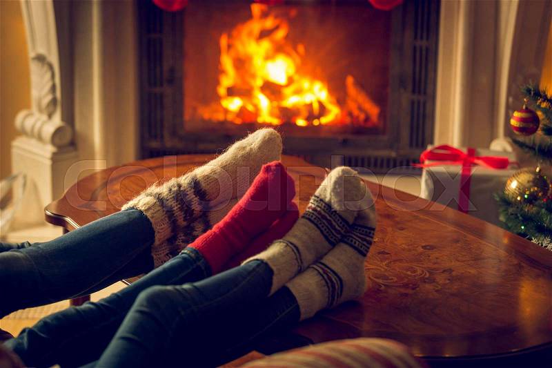 Family feet in woolen knitted socks warming by the fireplace at chalet, stock photo