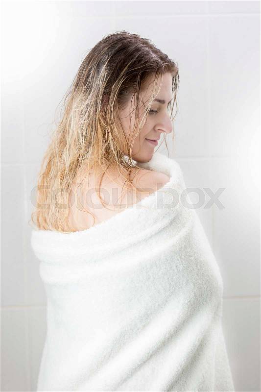Rear view of beautiful young woman with long hair wiping with towel after bathing, stock photo