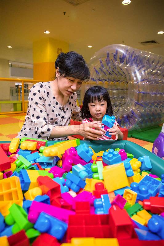 Asian Chinese mother and daughter playing blocks at indoor playground, stock photo
