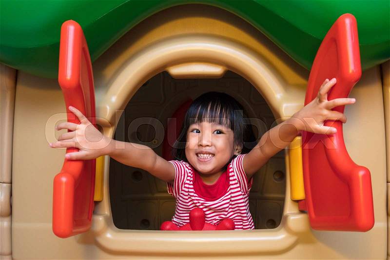 Asian Chinese little girl playing in toy house at indoor playground, stock photo
