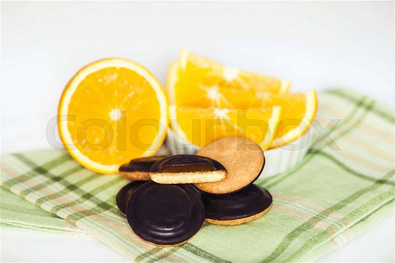 Heaps of Chocolate Chip Cookies with orange on green napkin and white background, stock photo