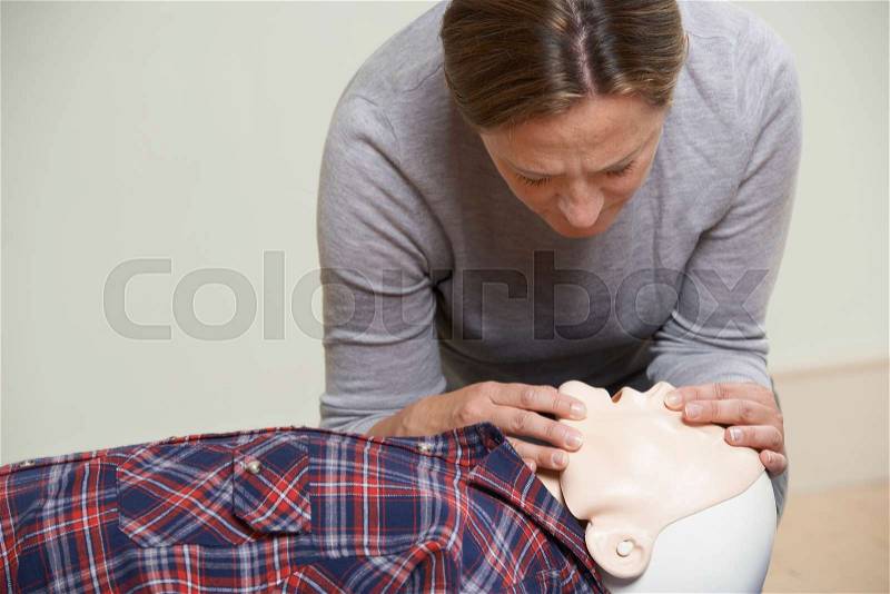 Woman In First Aid Class Performing Mouth To Mouth Resuscitation On Dummy, stock photo