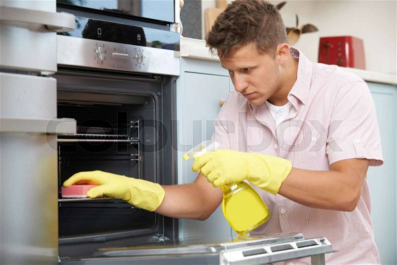 Fed Up Woman Cleaning Oven At Home, stock photo