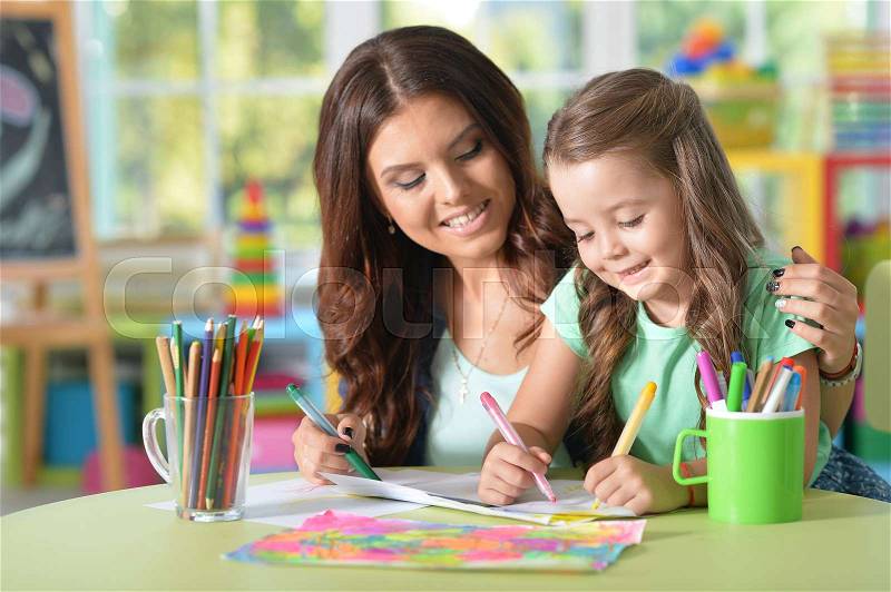 Portrait of a mother and daughter painting at home, stock photo