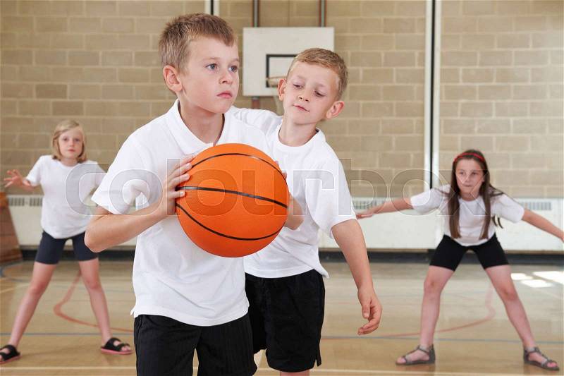 Elementary School Pupils Playing Basketball In Gym, stock photo