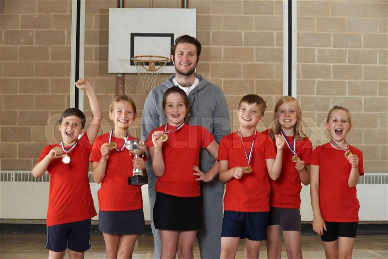 Victorious School Sports Team With Medals And Trophy In Gym, stock photo