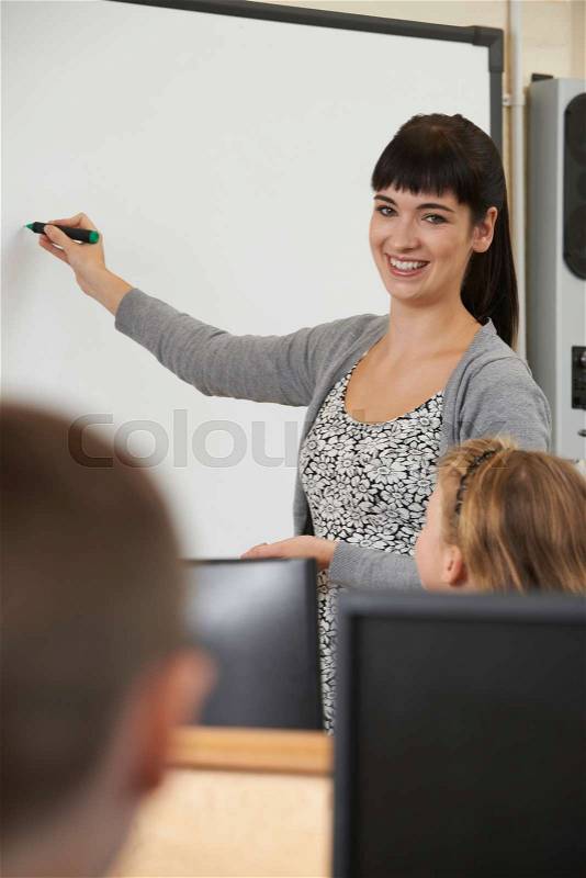 Teacher Writing On Interactive Whiteboard In Computer Lesson, stock photo