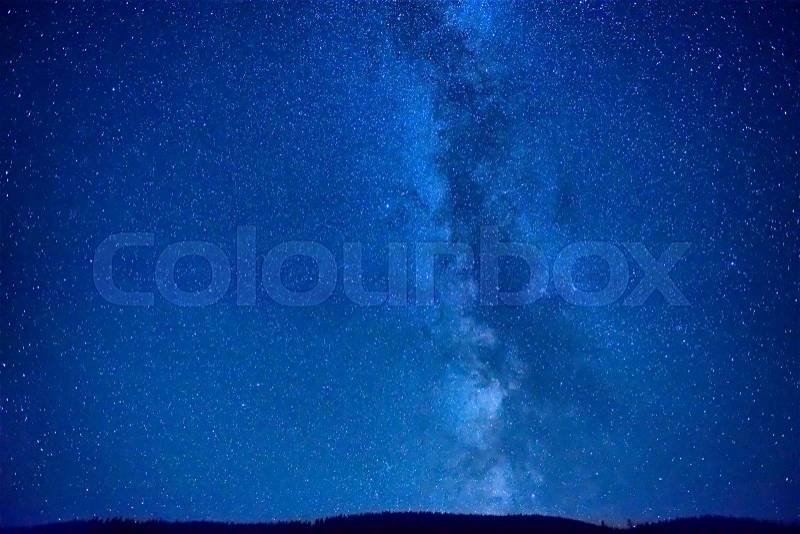 Night dark blue sky with many stars and milky way galaxy above a mountain, stock photo