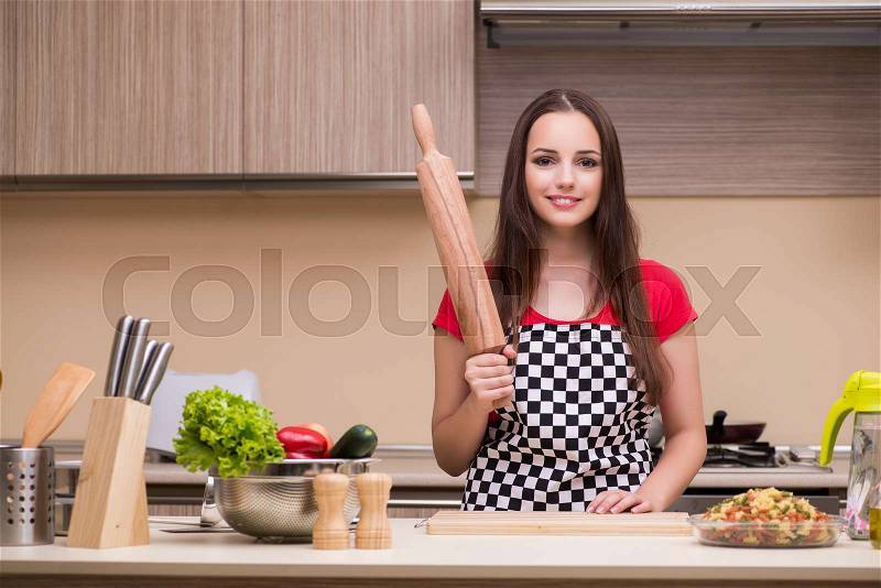 Young woman housewife working in the kitchen, stock photo