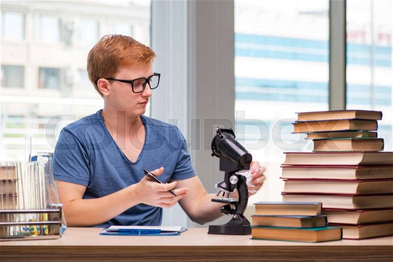 Young student tired and exhausted preparing for chemistry exam, stock photo
