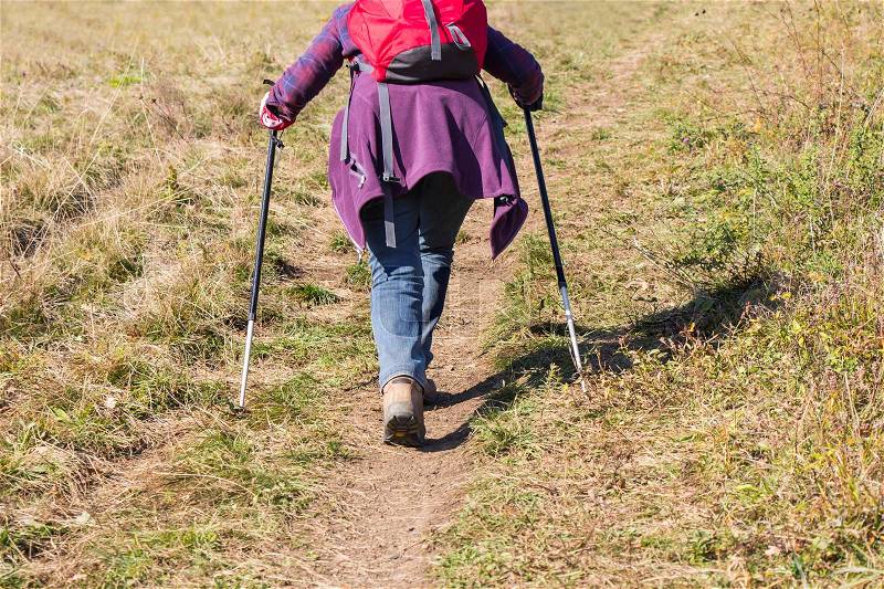 Older woman walking by hiking trail, stock photo