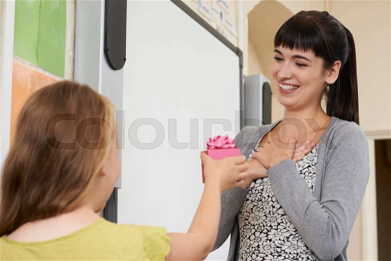 Female Pupil Giving Teacher End Of Term Gift, stock photo
