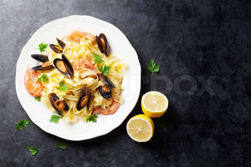 Pasta with seafood on stone table. Mussels and prawns. Top view with copy space, stock photo