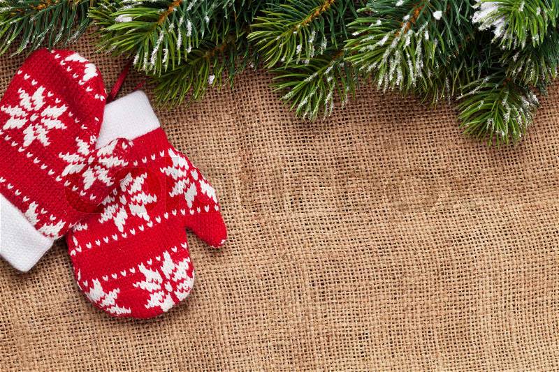 Christmas mittens decor and snow fir tree over burlap texture. Top view with copy space, stock photo