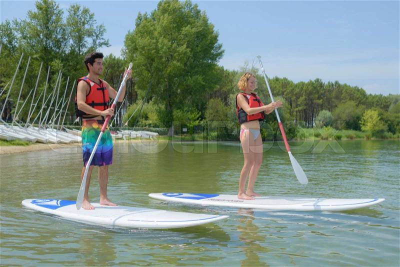 Couple standing on paddle board, stock photo