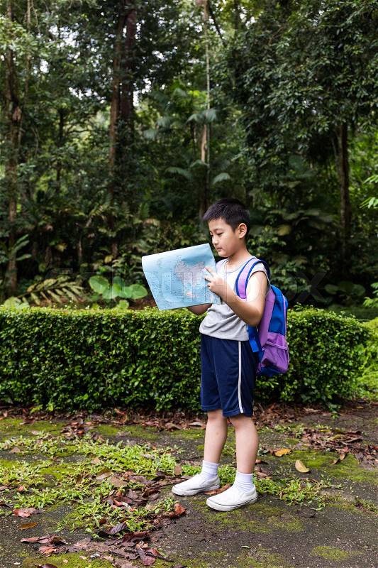 Asian Chinese little boy holding map in the forest searching for direction, stock photo