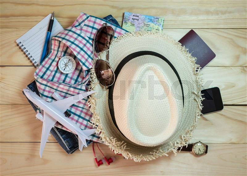 Stack of clothes and travel accessory on wooden plank. Travel concept, stock photo
