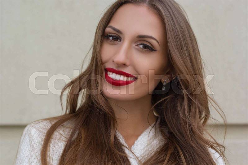 Portrait of beautiful gorgeous smiling woman with perfect skin posing near wall, stock photo