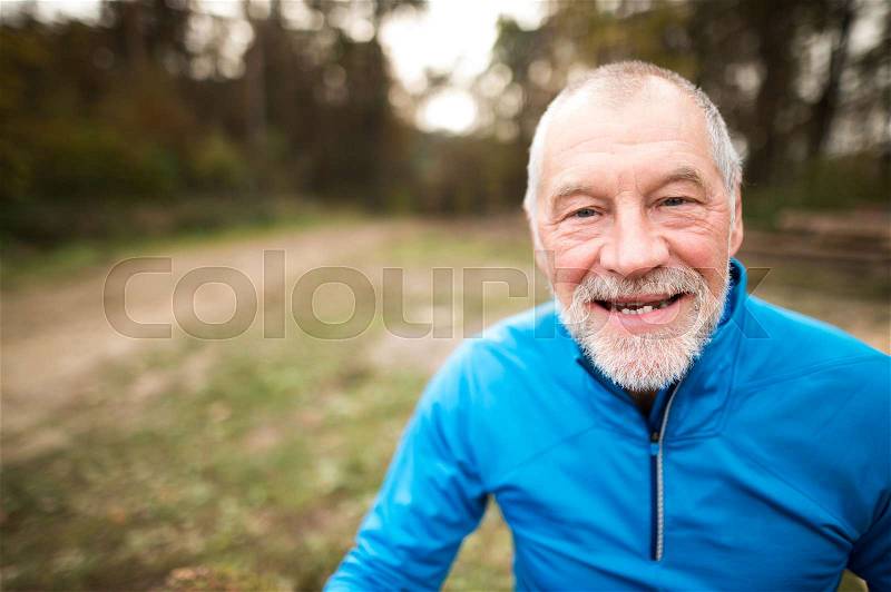 Close up of senior runner in nature. Man in blue sweatshirt, resting, smiling, stock photo