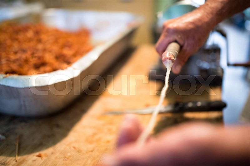 Unrecognizable man making sausages the traditional way using sausage filler. Homemade raw sausage, stock photo