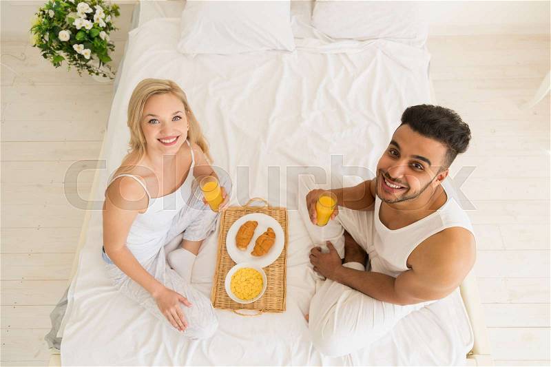 Young Couple Breakfast Sitting In Bed, Happy Smile Young Hispanic Man And Woman Morning Top Angle View Lovers Bedroom, stock photo