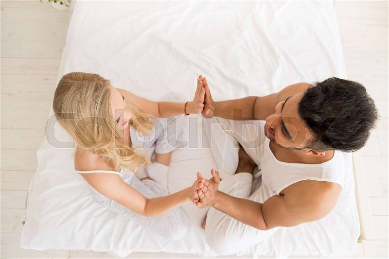 Young Couple Hold Hands Sitting In Bed, Happy Smile Young Hispanic Man And Woman Top Angle View Lovers Bedroom, stock photo