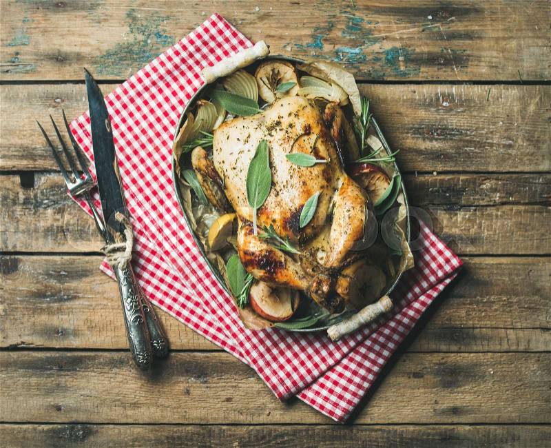 Oven roasted whole chicken in tray over wooden background, stock photo