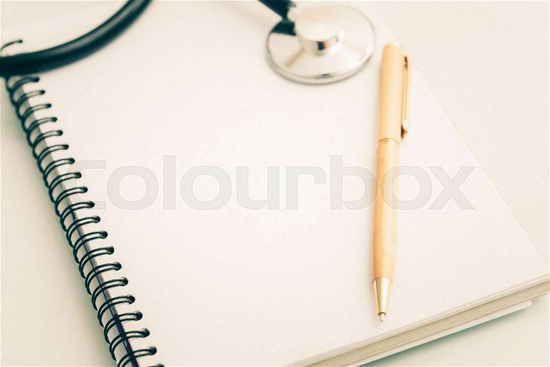 Stethoscope and pen on book with vintage Film Grain filter, stock photo