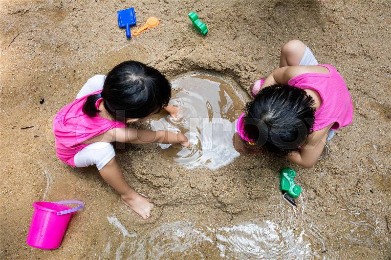 Asian Chinese little sister playing sand at creek, stock photo