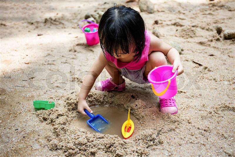 Asian Chinese little girl playing sand at creek alone, stock photo
