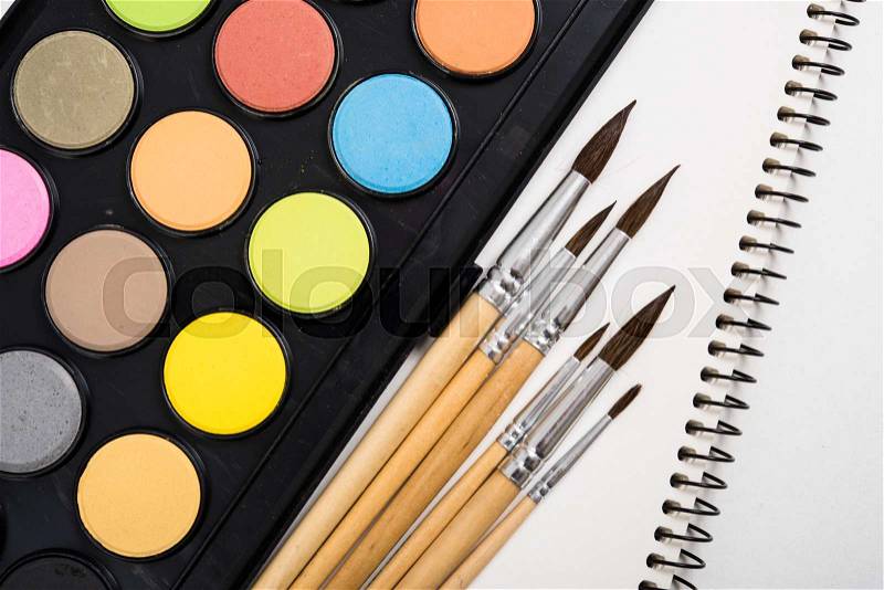Watercolor paint set and new brushes with clean paper on artist\'s work desk, creative artistic tools isolated on white background closeup, stock photo