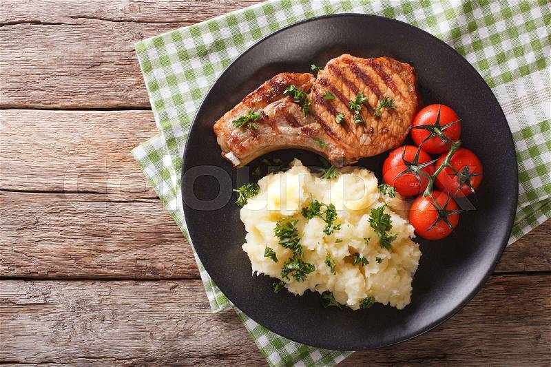 Grilled pork loin with mashed potatoes and tomato close-up on a plate. Horizontal view from above , stock photo