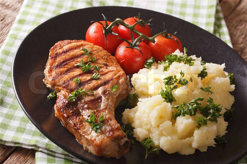 Grilled pork steak with garnish mashed potatoes and tomatoes close-up on a plate. horizontal , stock photo